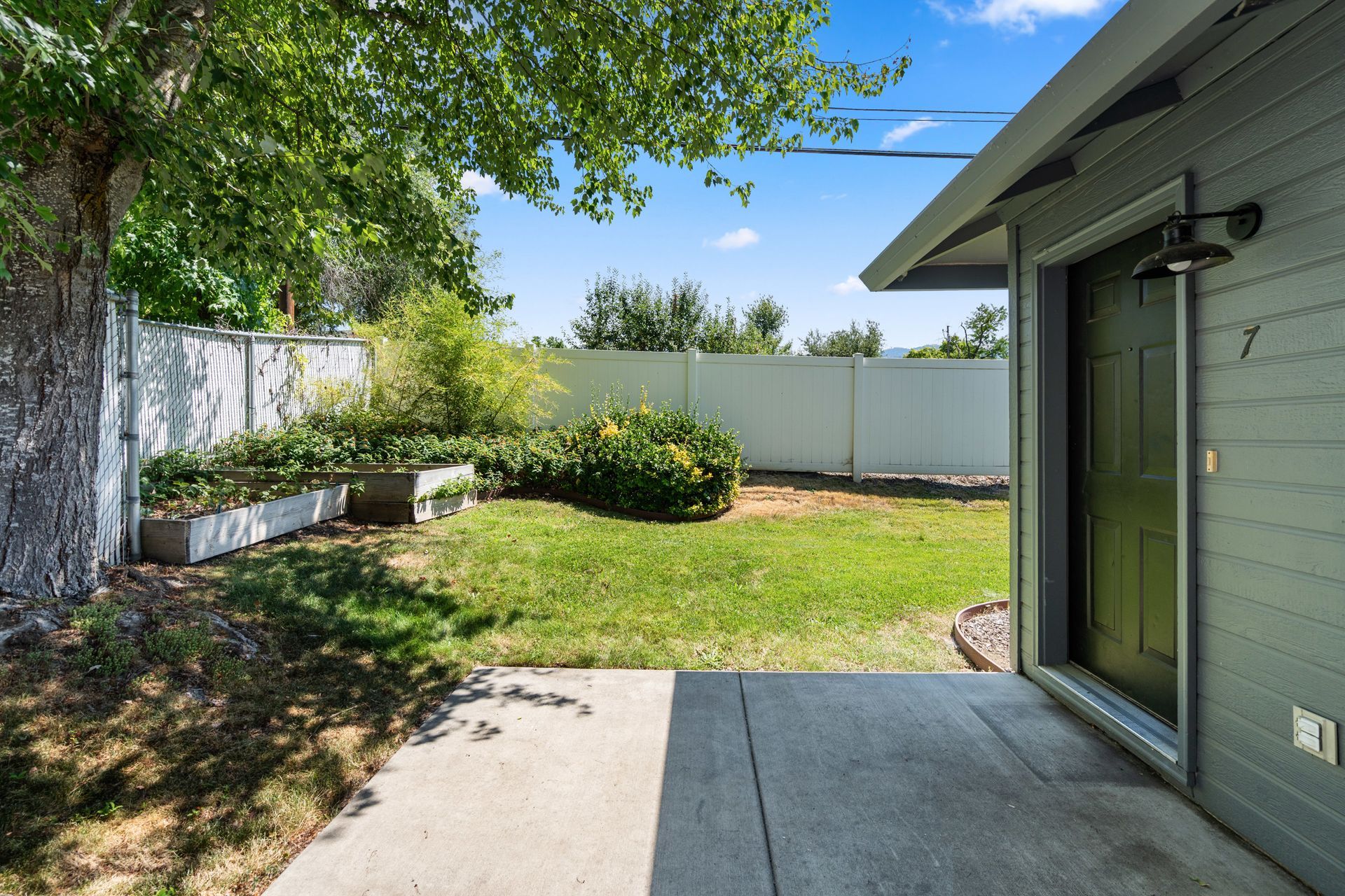 The backyard of a house with a white fence and a patio