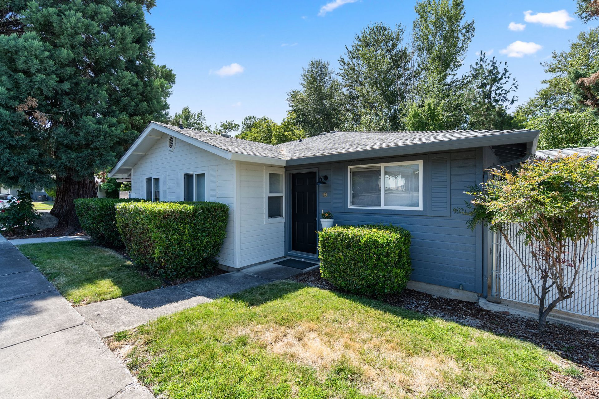 A white house with a blue roof and a white fence