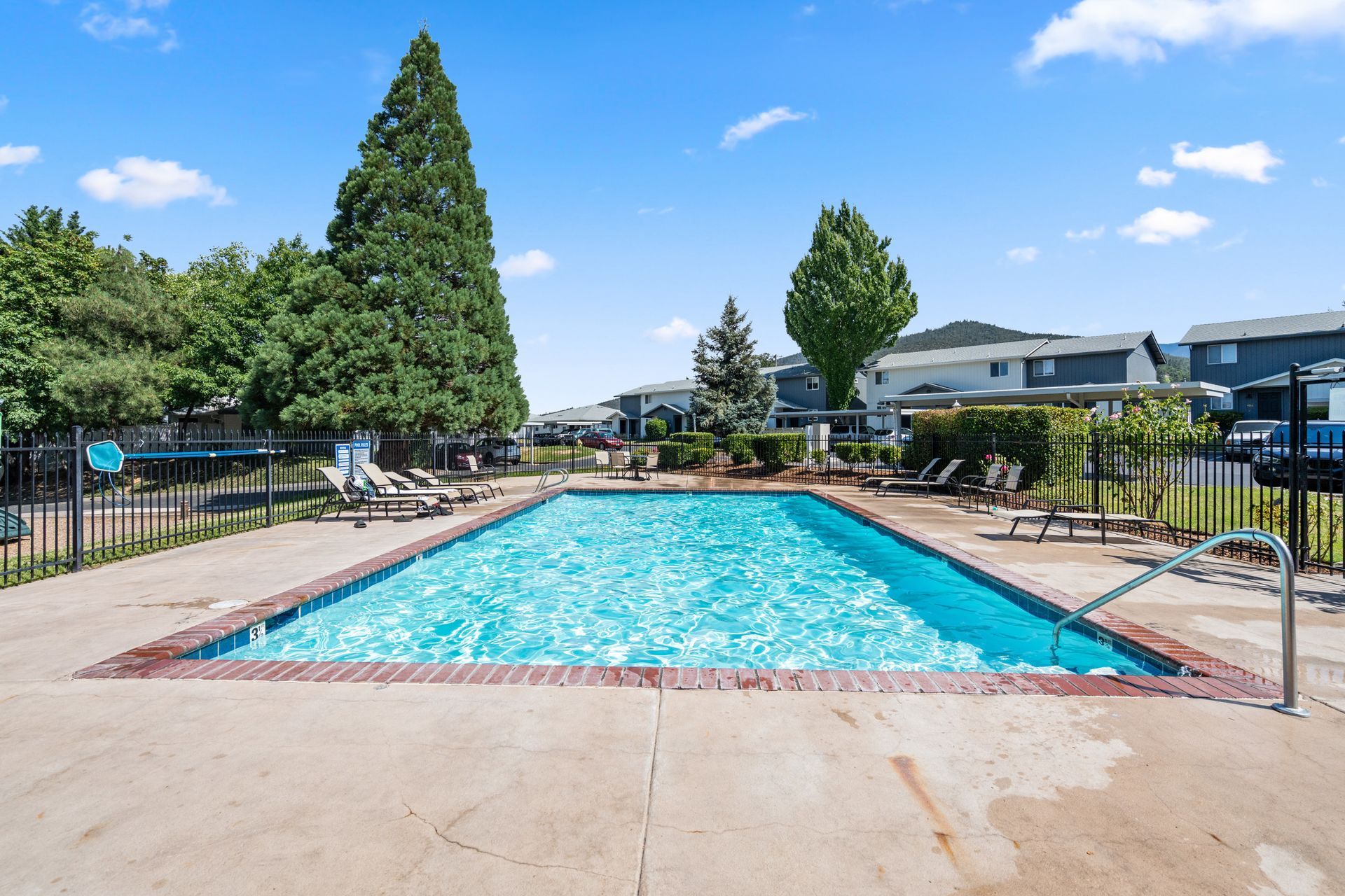A large swimming pool is surrounded by a fence and chairs.