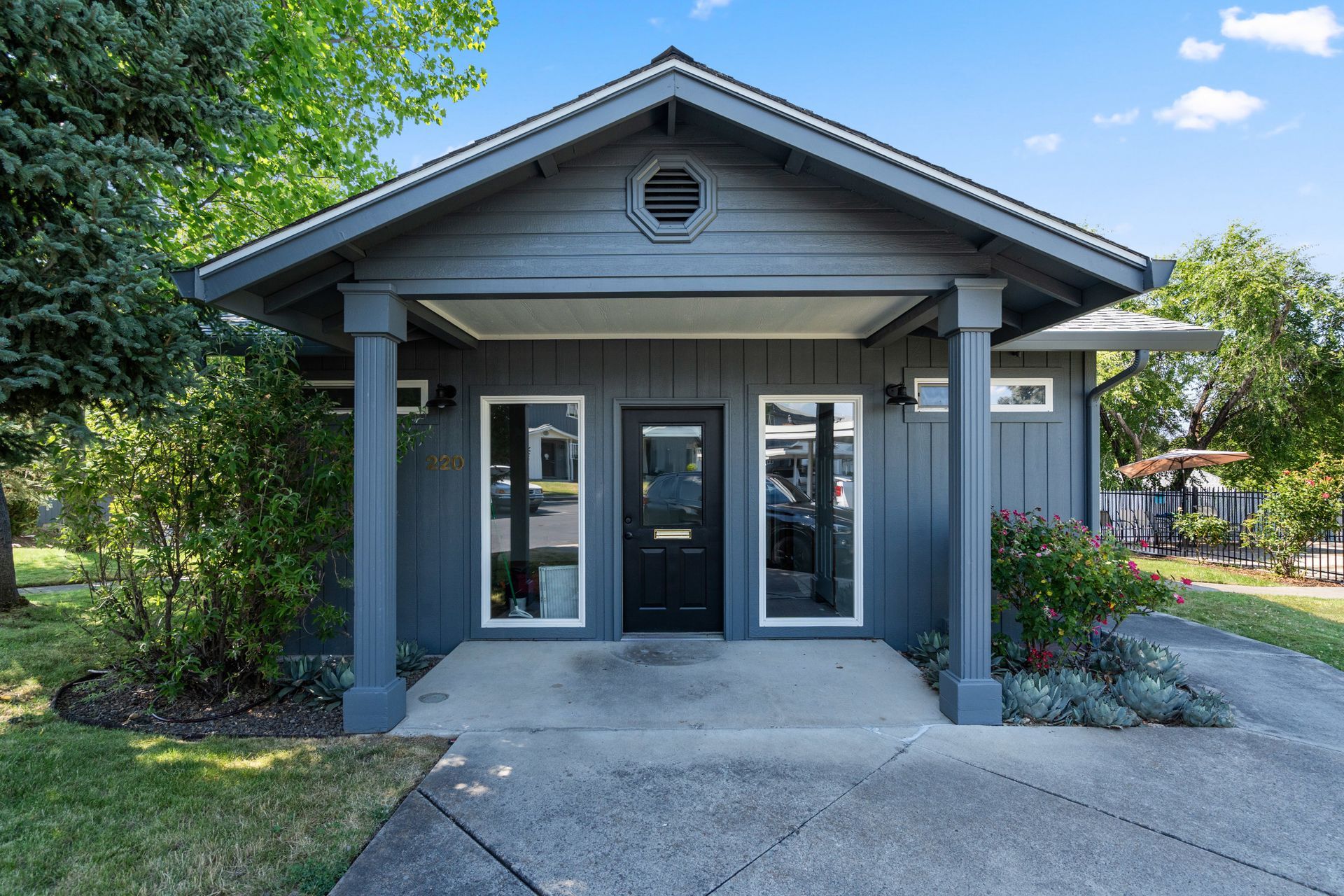 A gray house with a porch and a black door
