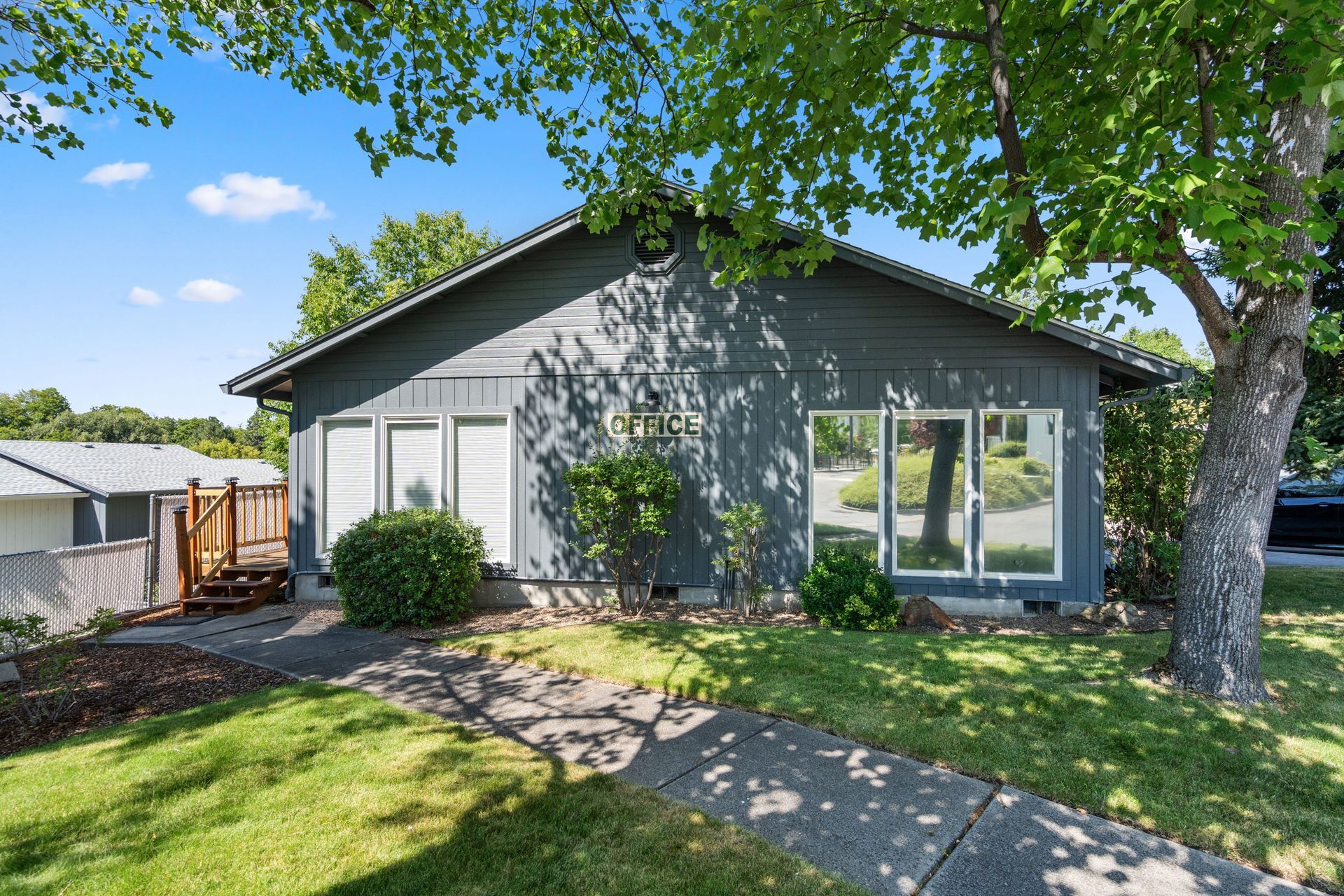 A gray house with a lot of windows and a tree in front of it.
