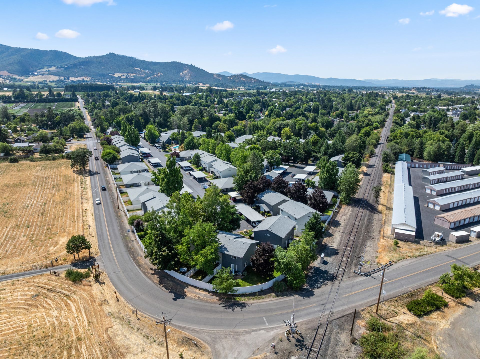 An aerial view of a residential area surrounded by trees and a road.