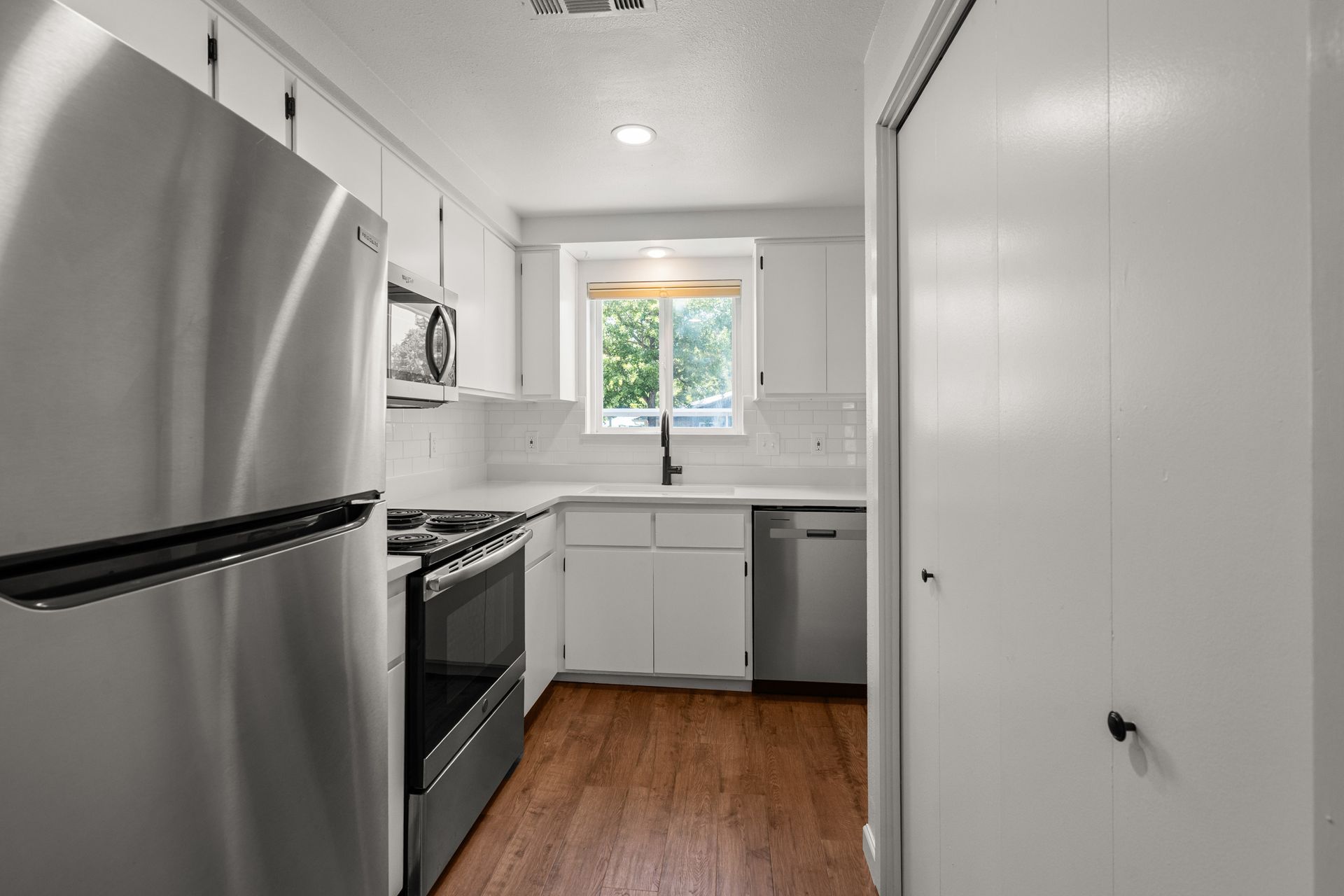 A kitchen with stainless steel appliances and white cabinets.