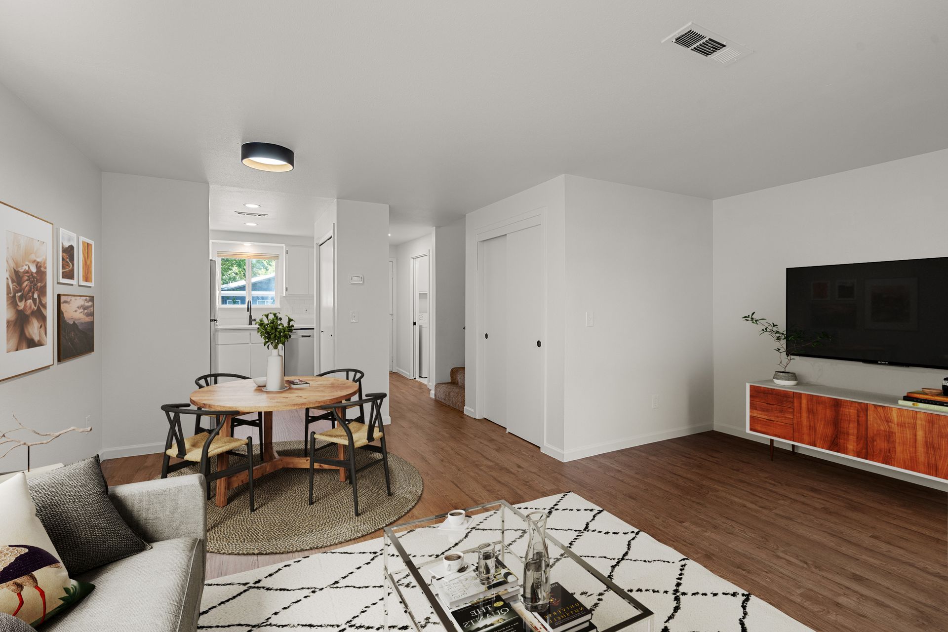 A living room with a couch , table , chairs and a flat screen tv.
