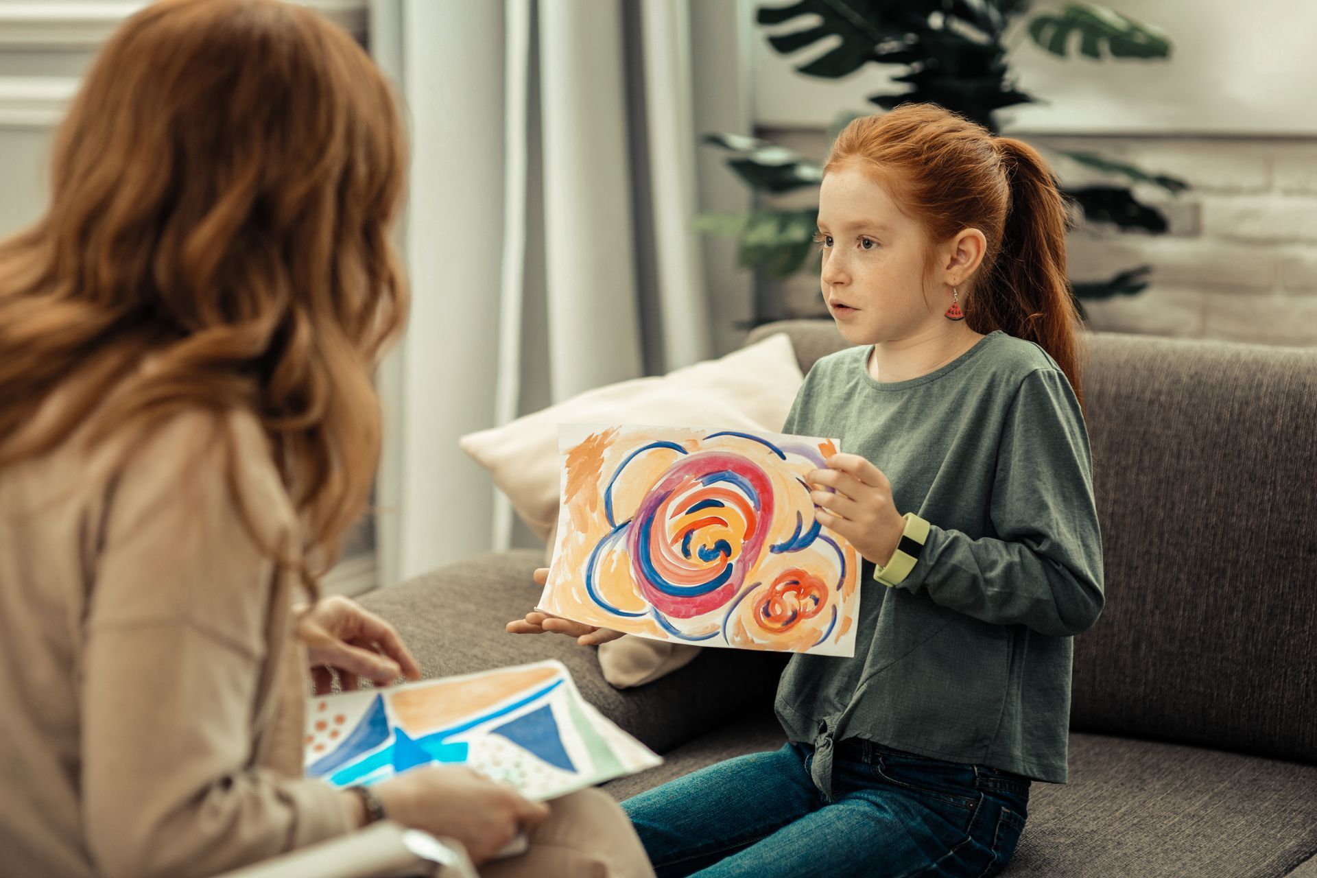 a girl showing her artwork to an art therapist