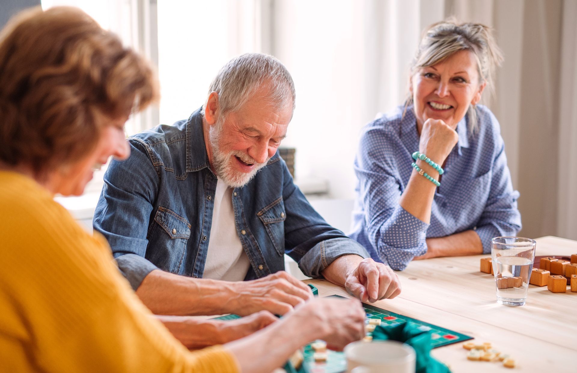 A group of elderly people are sitting at a table playing a board game.