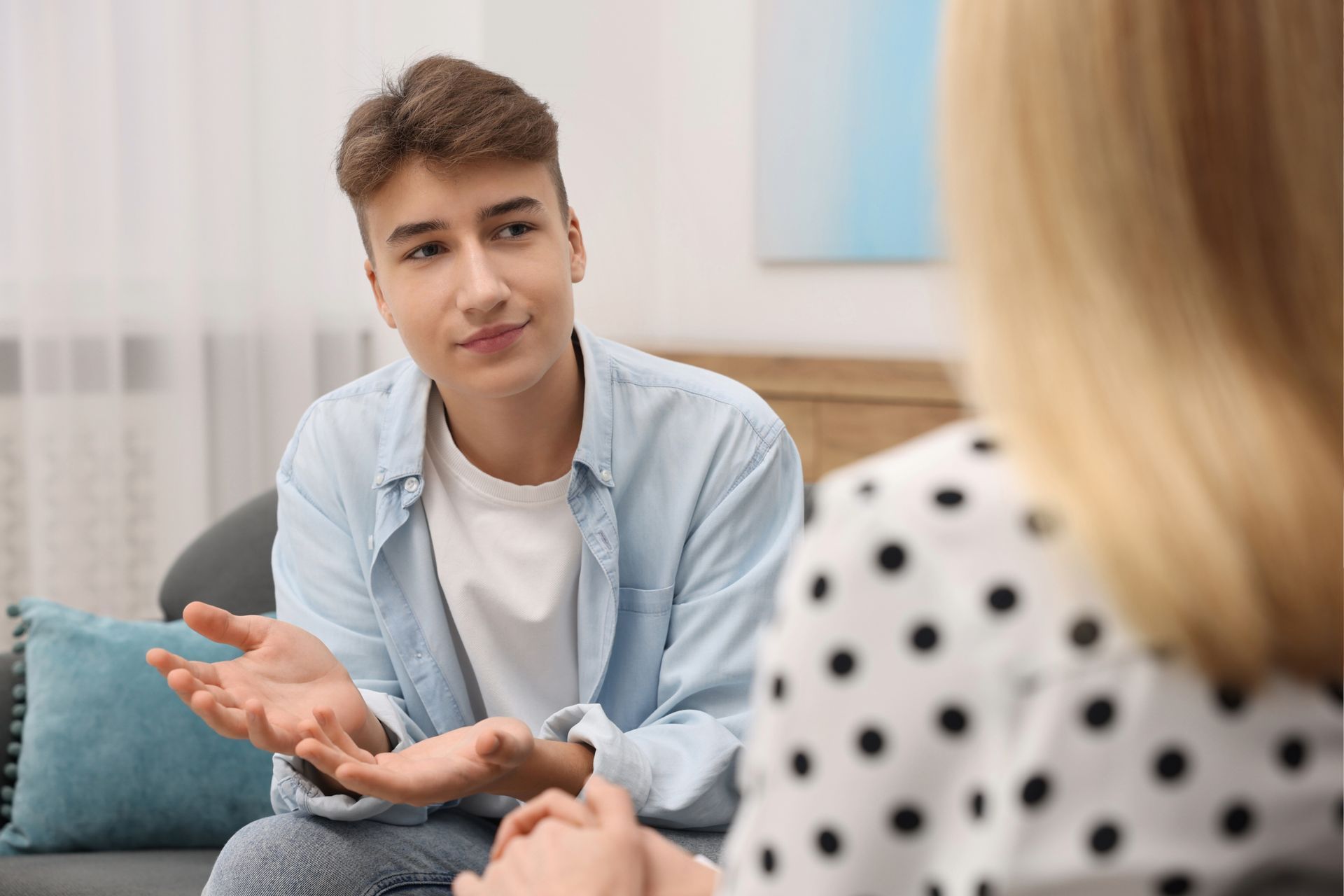 A young person talking to someone, gesturing with hands in a counseling session.