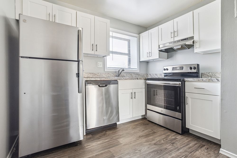 Kitchen with stainless steel appliances, white cabinets, and gray walls.