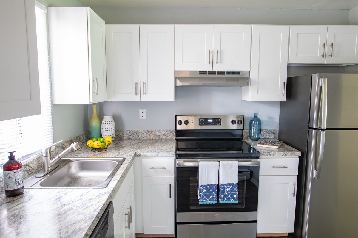 White kitchen cabinets with stainless steel appliances and granite countertops.