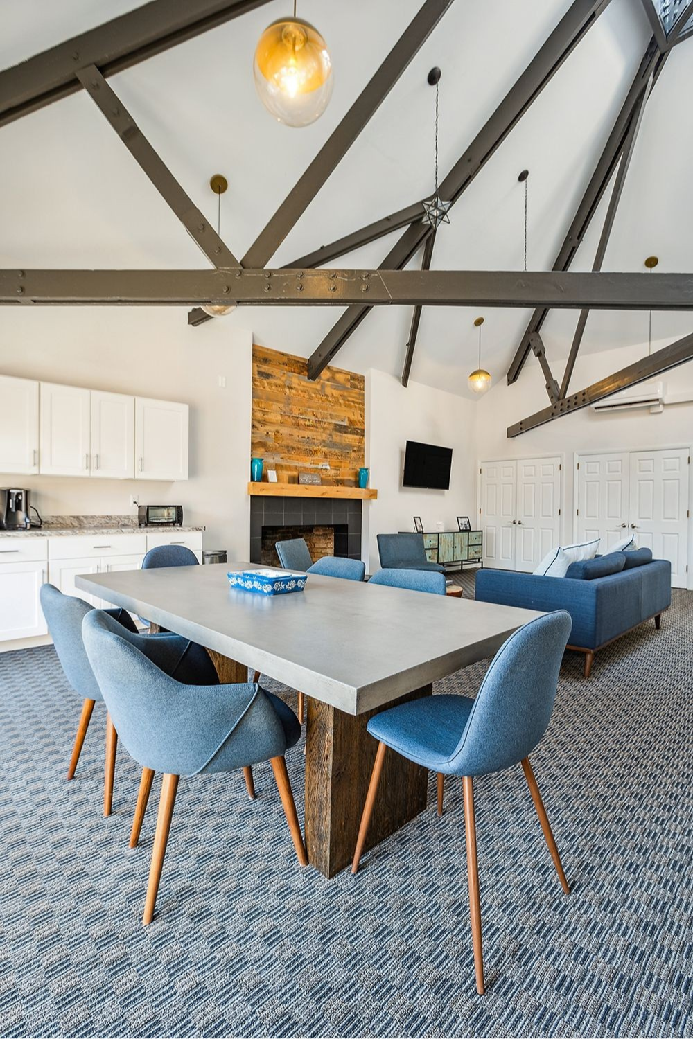 A modern dining area with a table and blue chairs, and a fireplace with a TV.