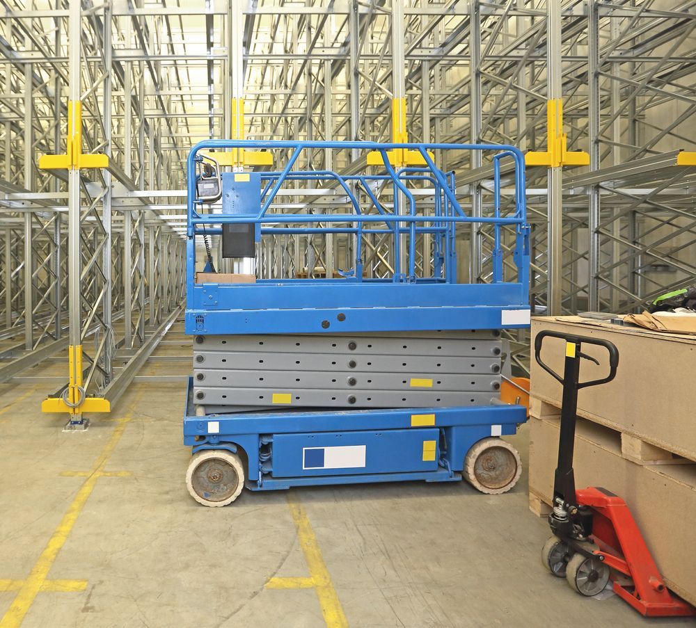 A blue scissor lift is parked in a large warehouse — MPE Adventure Quads & Bikes In Thornton, NSW