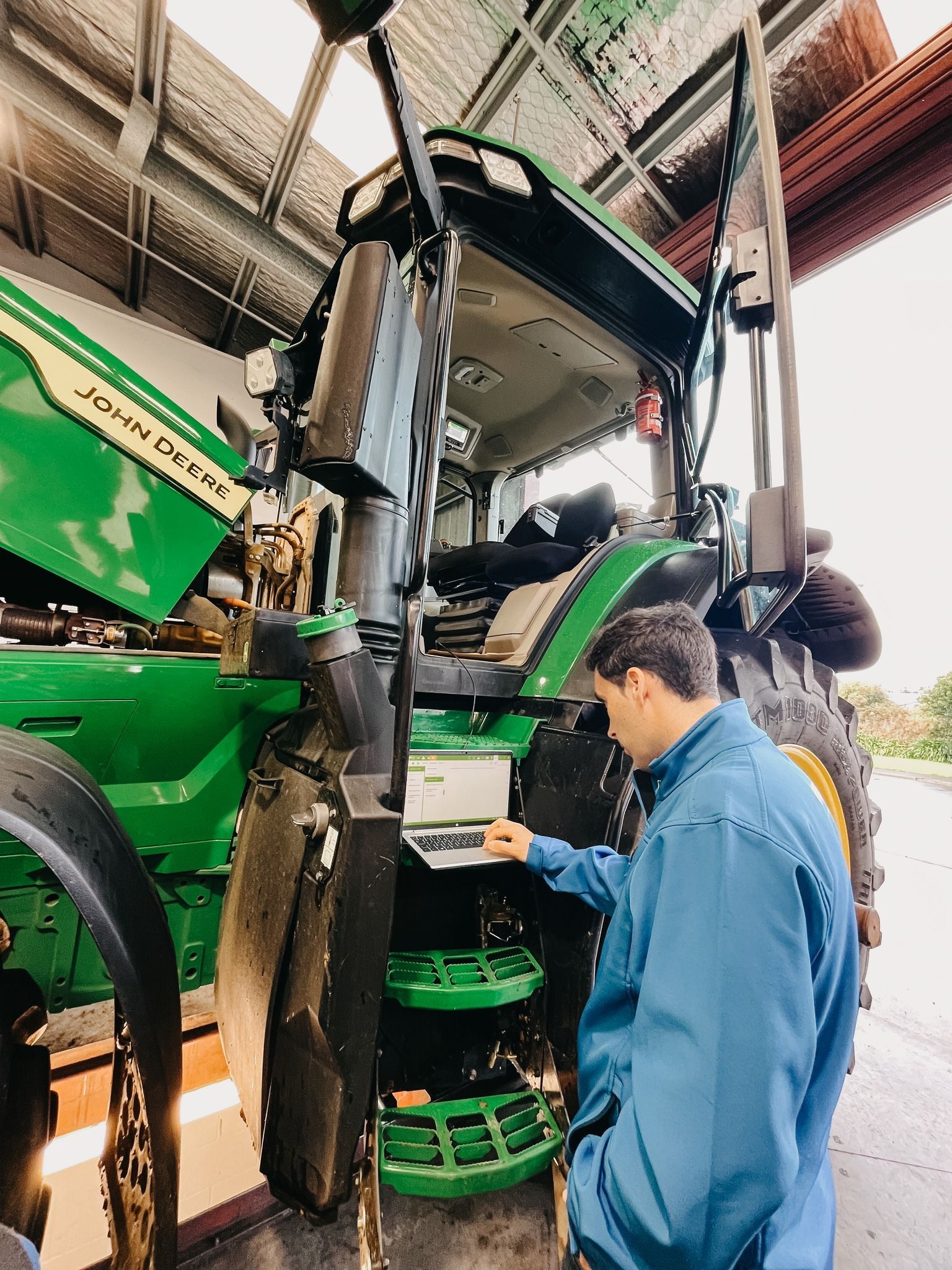A Man is Working on a Green Tractor in a Garage — MPE Adventure Quads & Bikes In Thornton, NSW