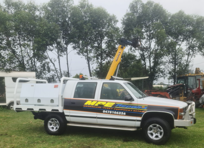 White utility truck with yellow boom lift; MPE Electrics logo on the side, parked on grass - MPE Adventure Quads & Bikes In Thornton, NSW
