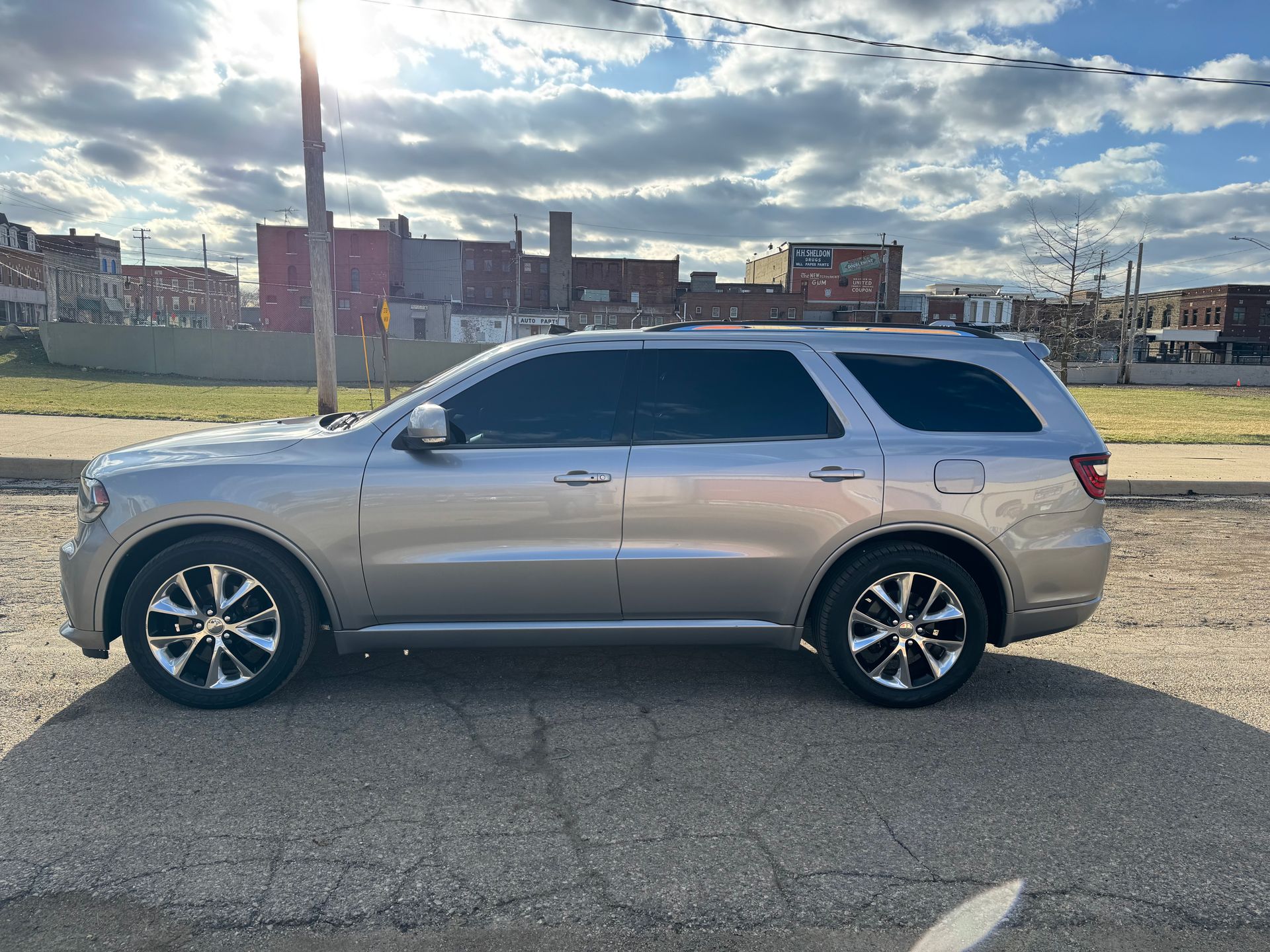 A silver dodge durango is parked on the side of the road in a parking lot.