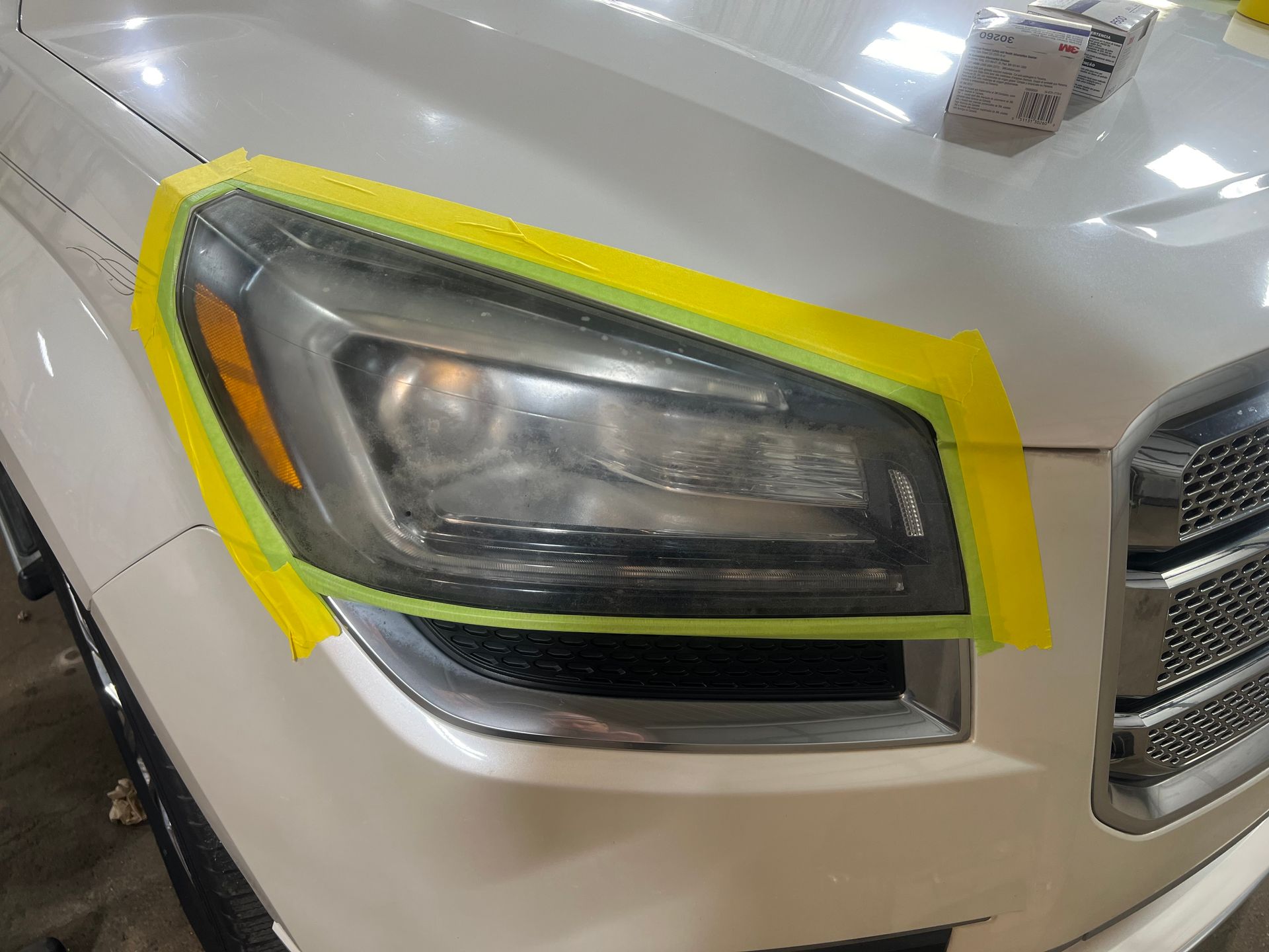 A close up of a car headlight with yellow tape on it.