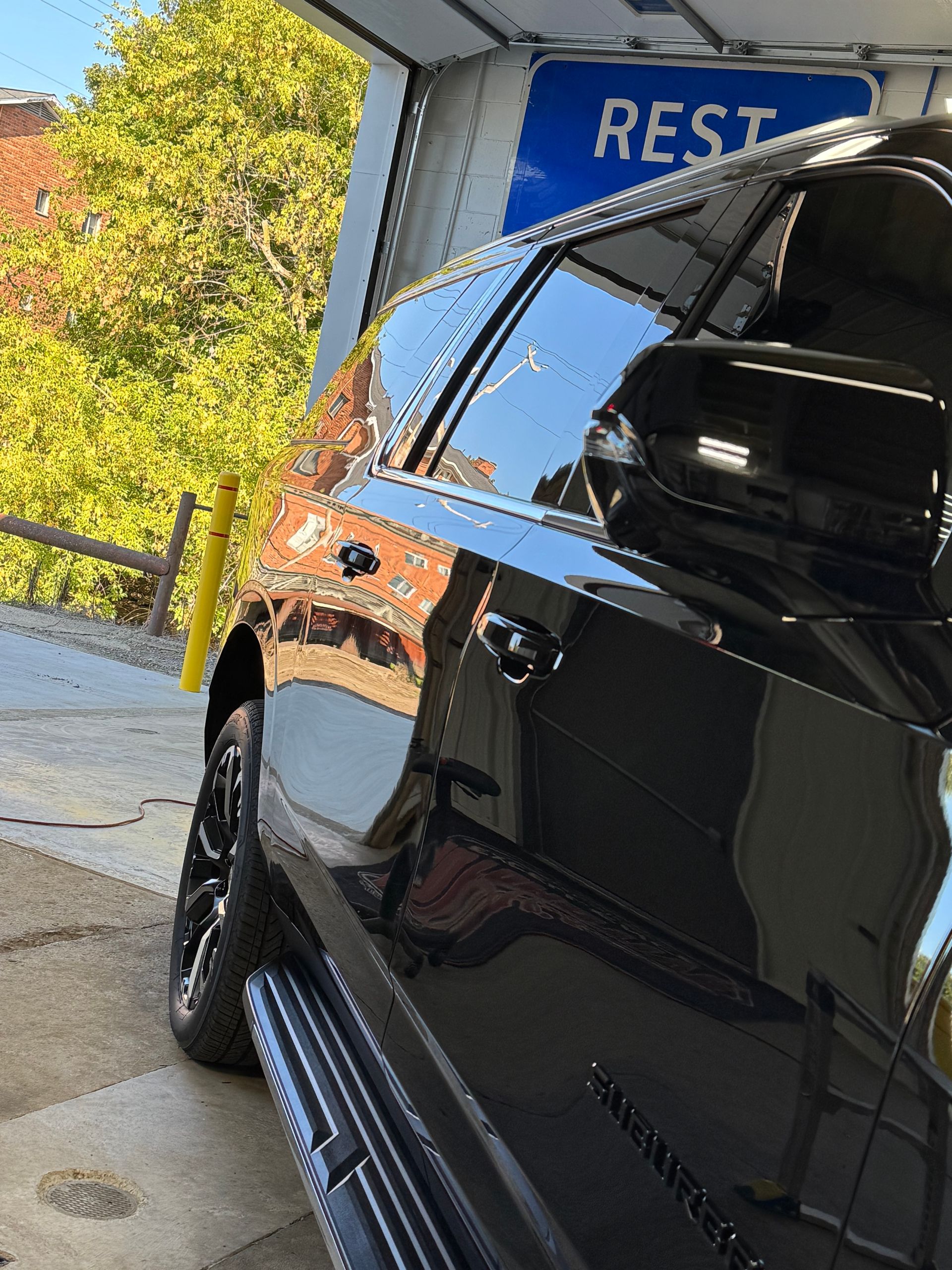 Black SUV parked near a building. Reflective surface, with a 