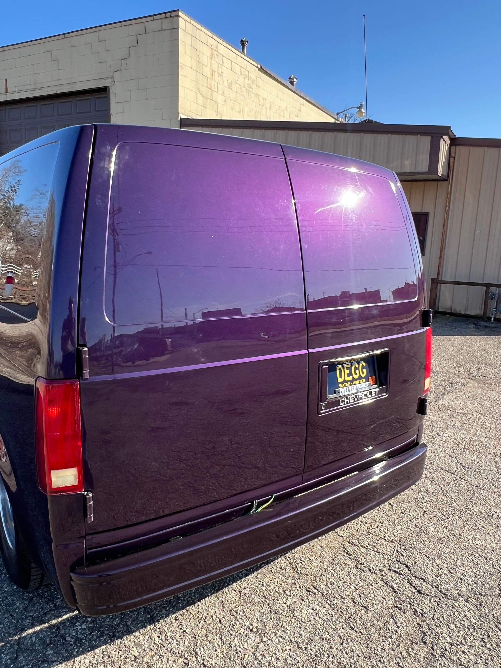 A purple van is parked in front of a building