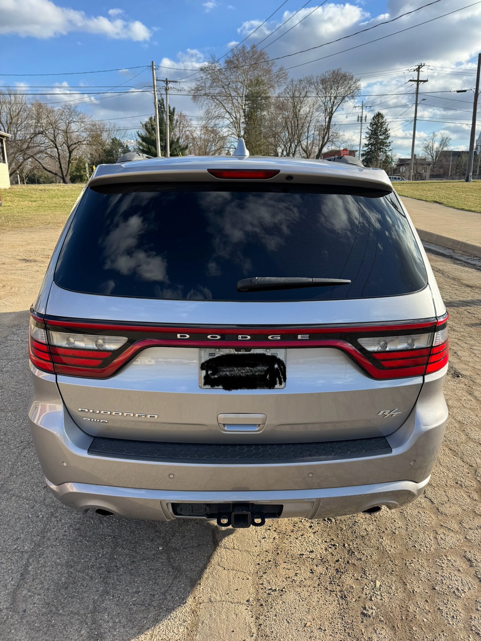 The back of a silver dodge durango is parked on the side of the road.