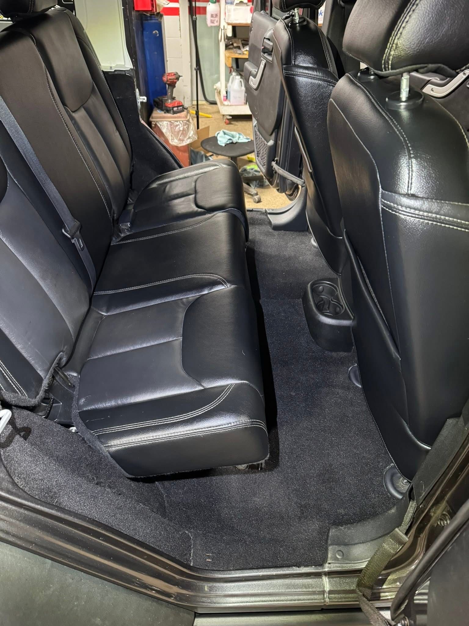 The back seat of a car with black leather seats.