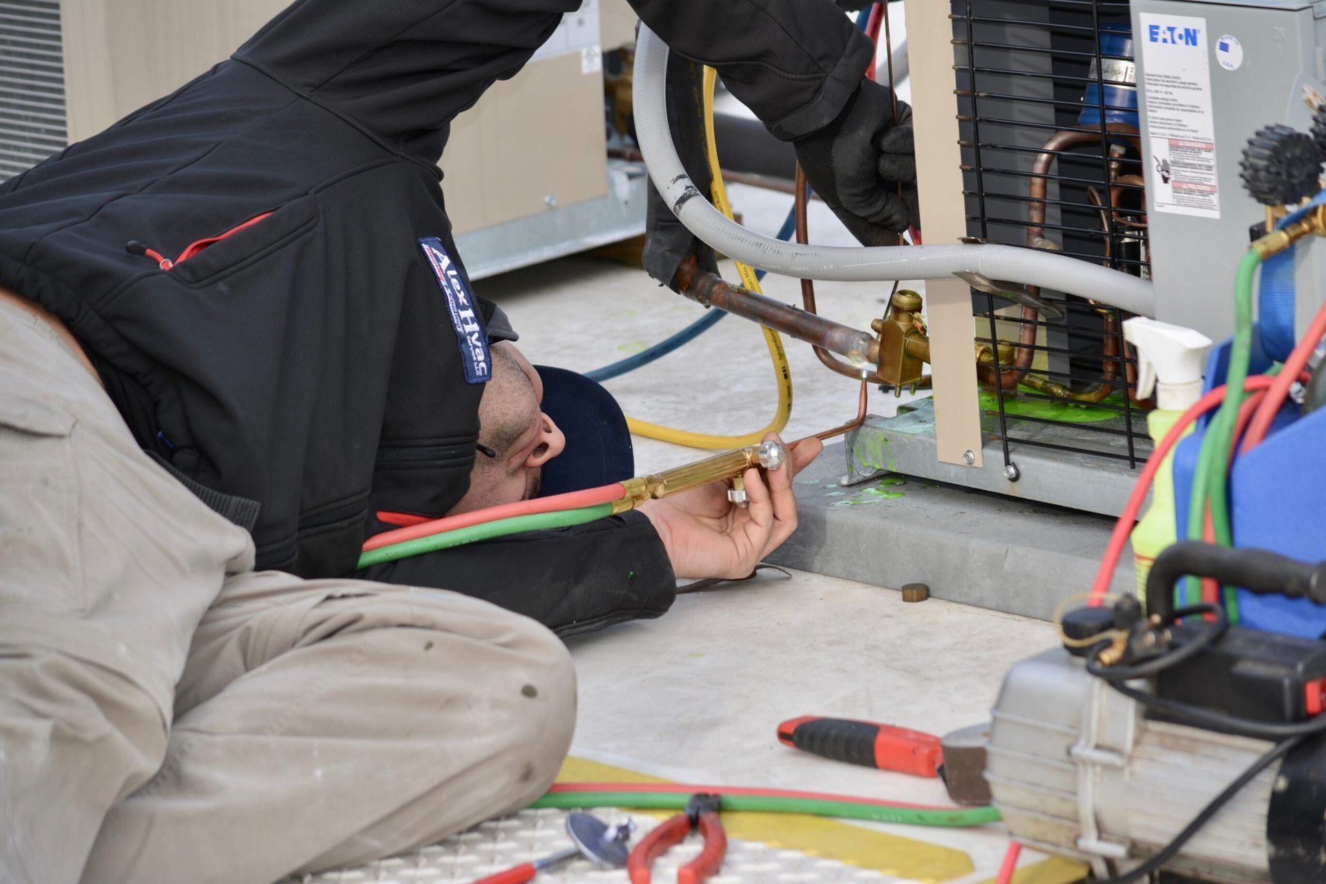 HVAC repair technician welding copper lines on outdoor unit for Alex HVAC Service LLC