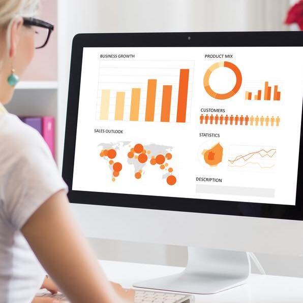 A woman is sitting in front of a computer with graphs on the screen