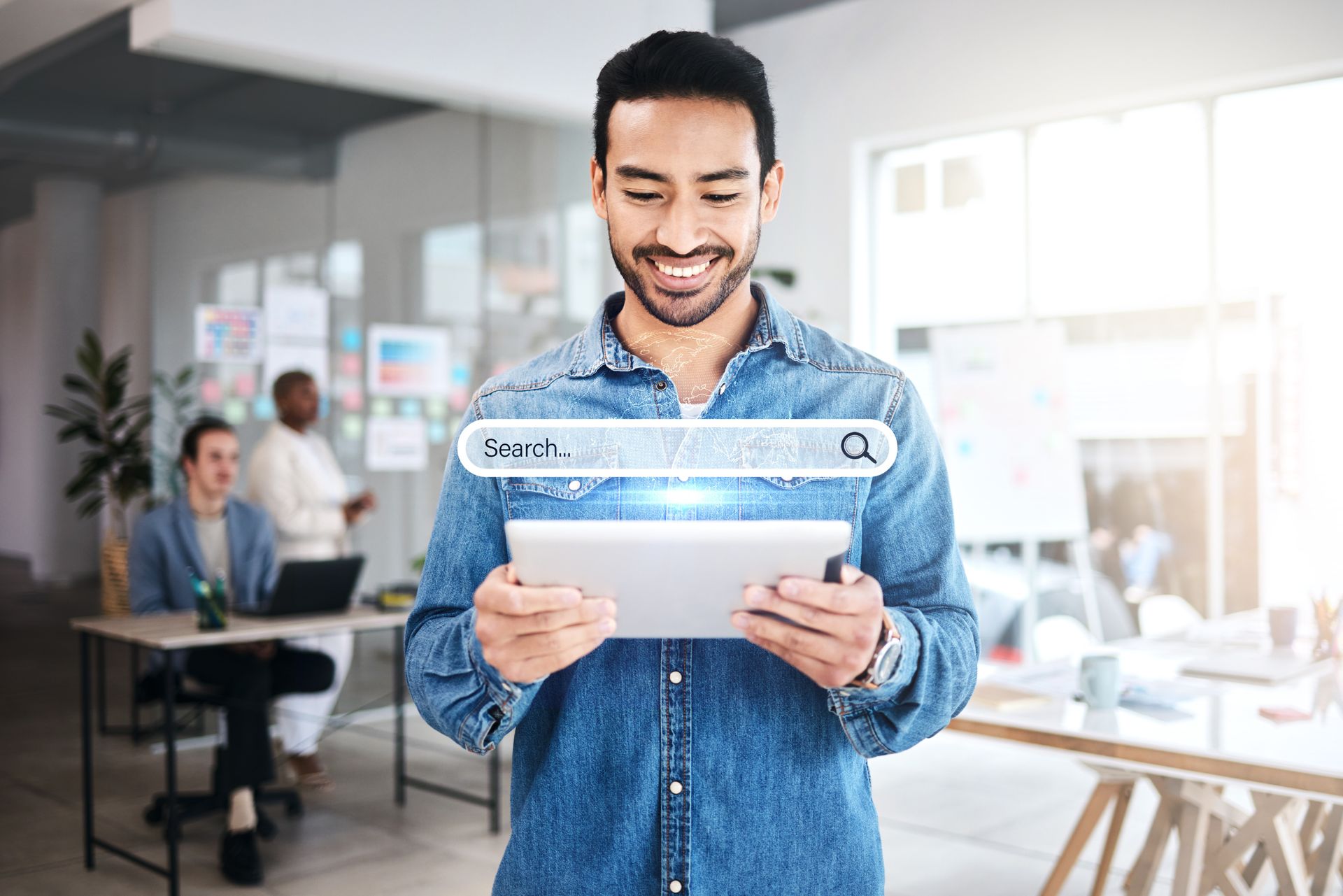 A man is holding a tablet with a search bar on it.