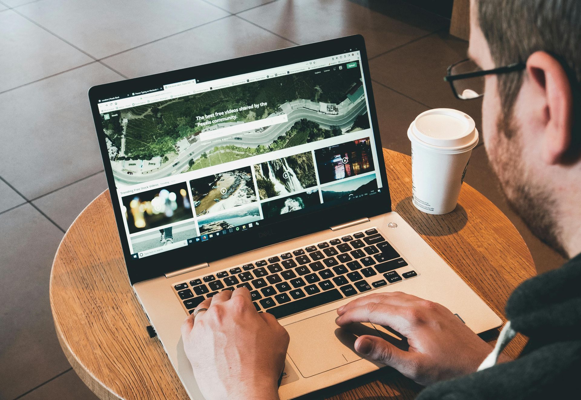 A man is sitting at a table using a laptop computer.