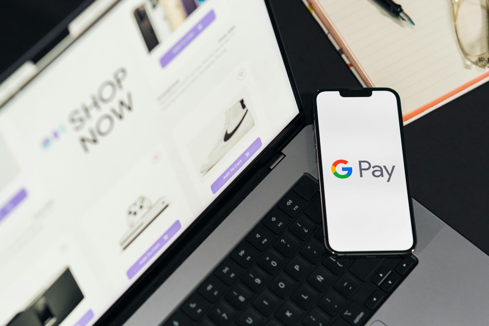 A phone with the google pay logo on it is sitting on a laptop.