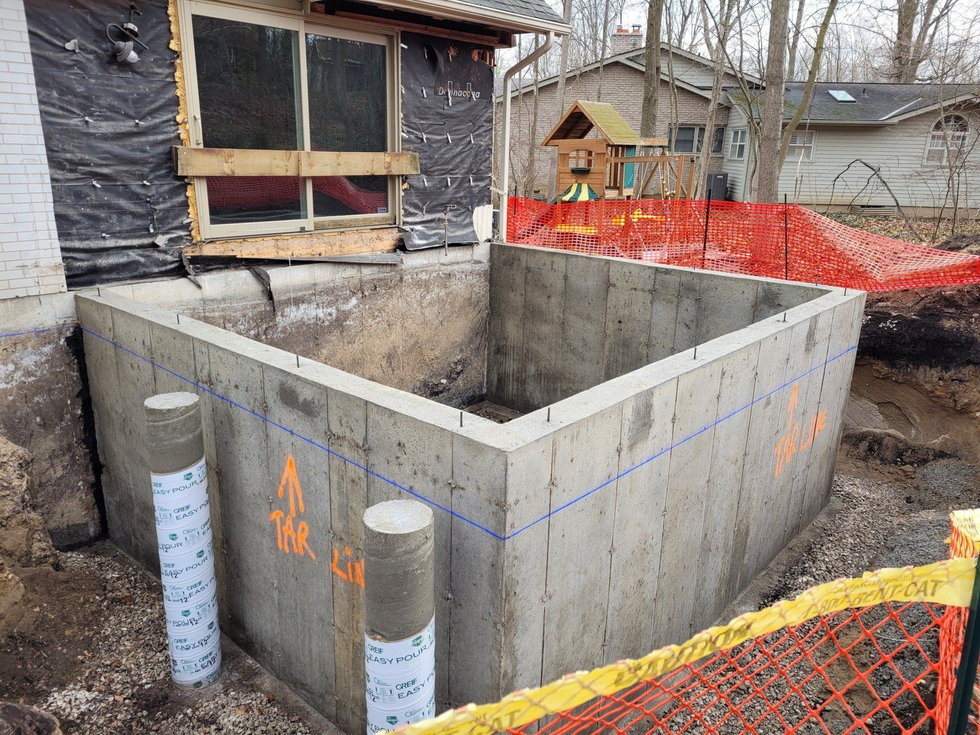 A large concrete structure is being built in front of a house.