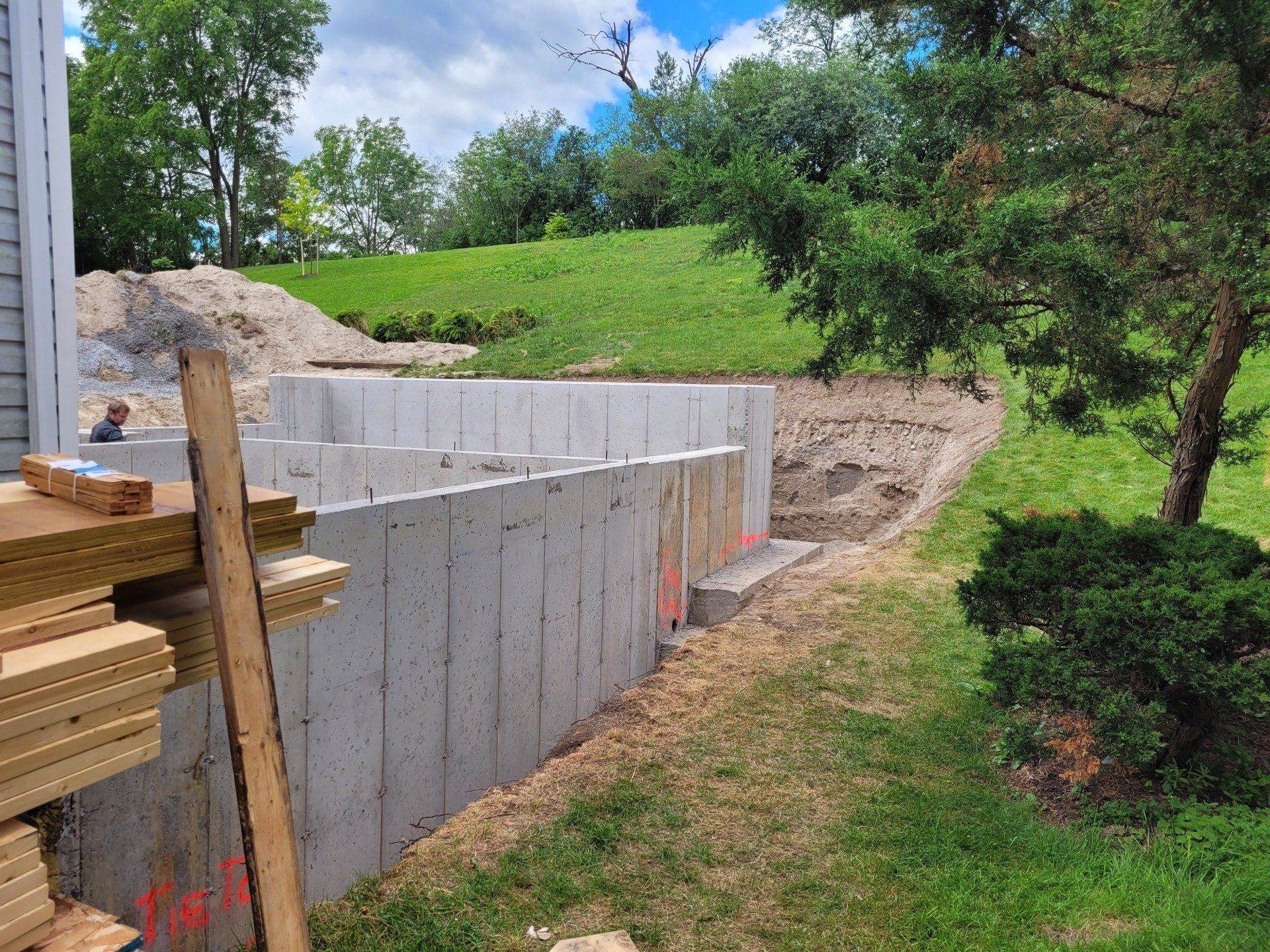 A concrete wall is being built in the backyard of a house.