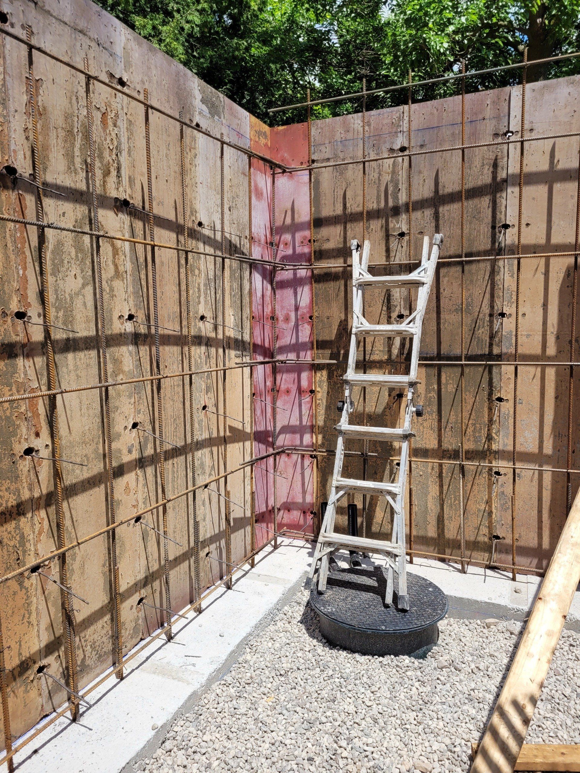 A ladder is sitting in front of a wall that is being built.