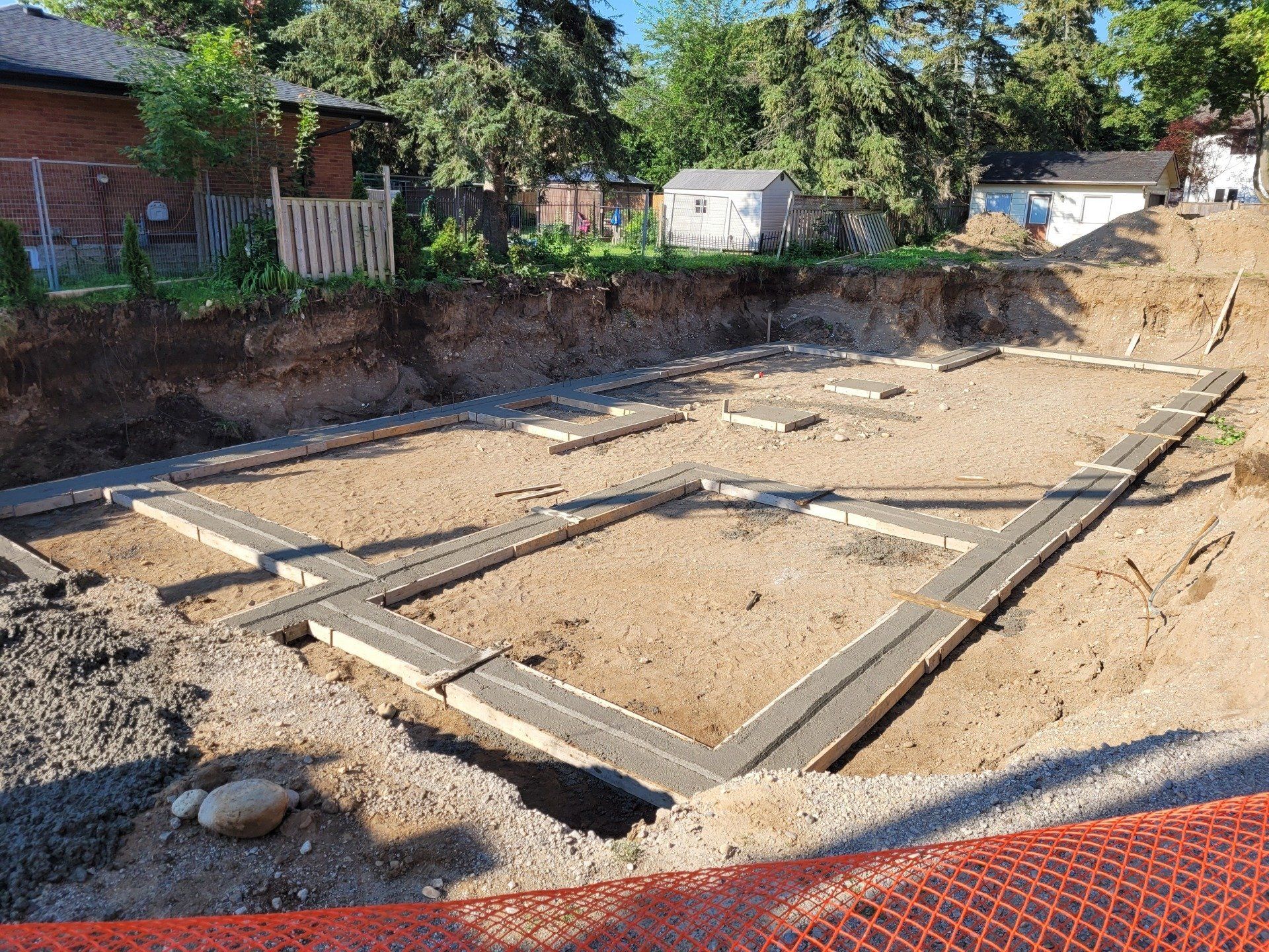 A construction site with a fence and a house in the background.