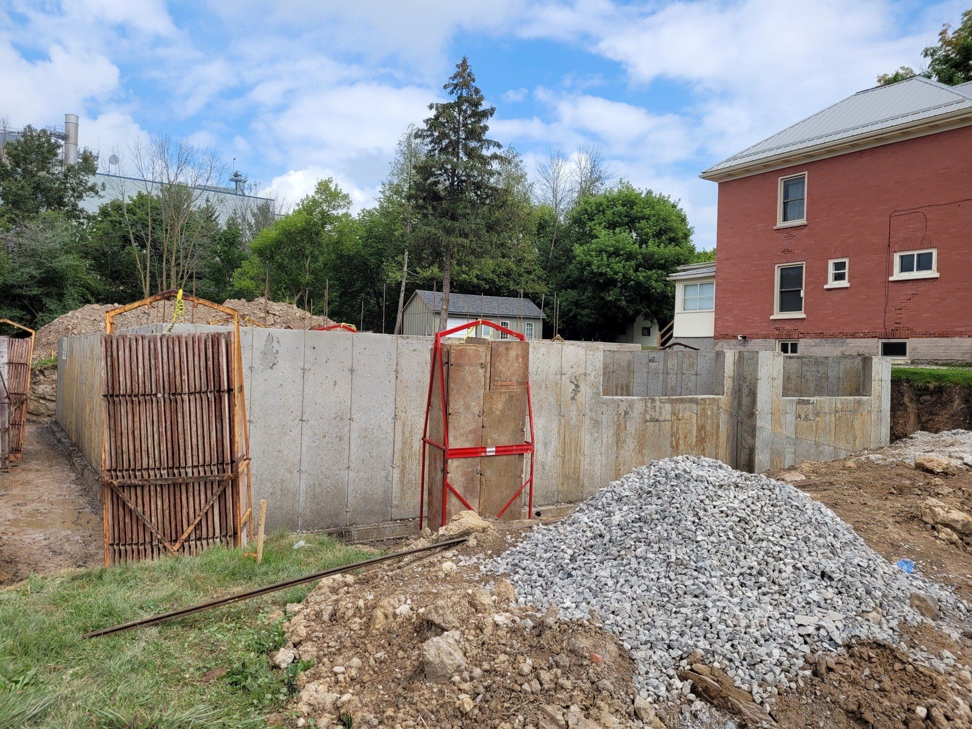 A concrete wall is being built in front of a brick house.