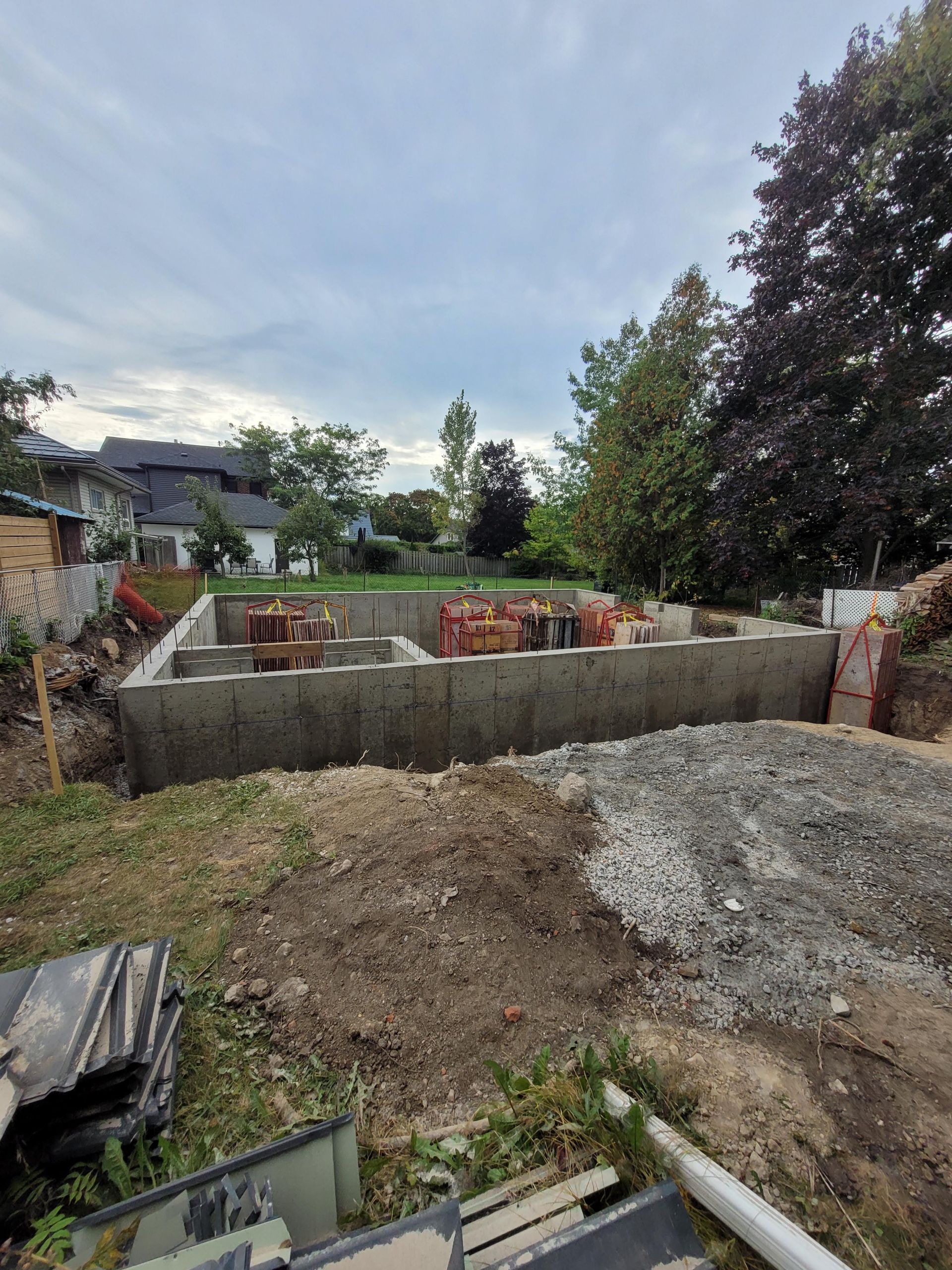 A concrete foundation is being built in the backyard of a house.