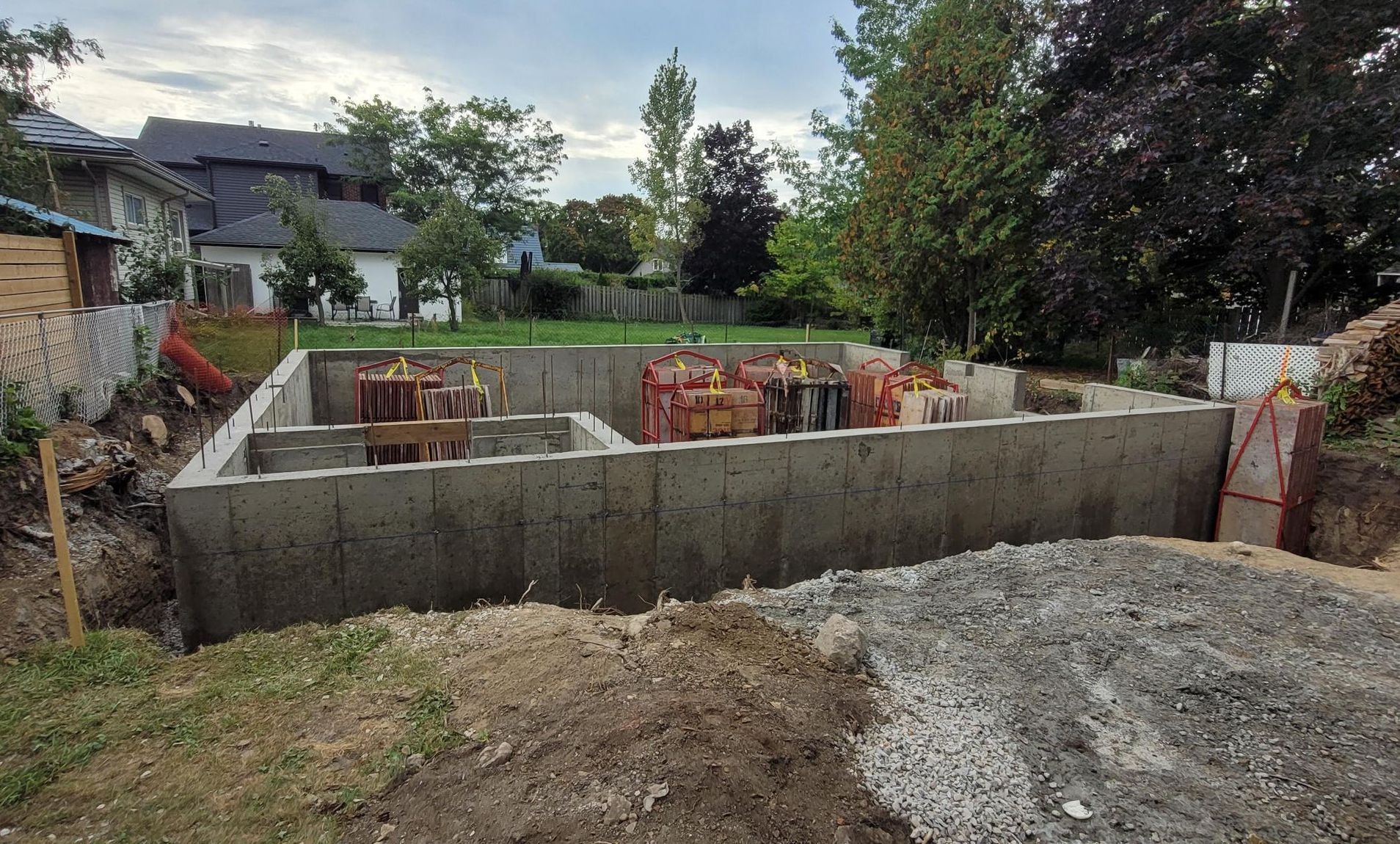 A concrete foundation is being built in the backyard of a house.