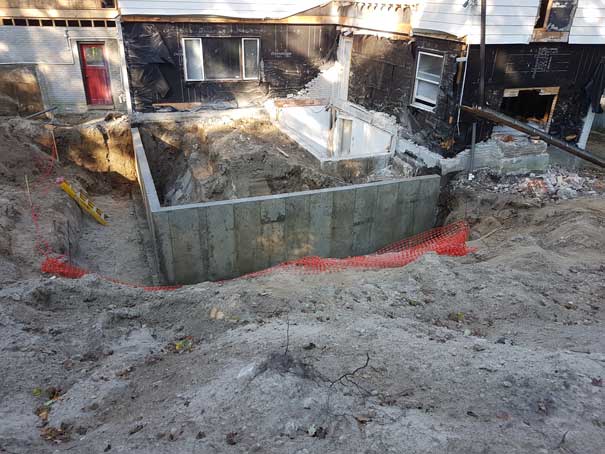 A concrete wall is being built in front of a house.