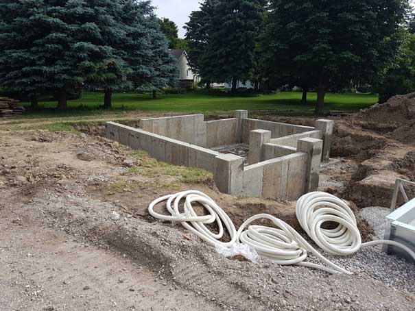 A concrete foundation is being built in a yard with trees in the background.