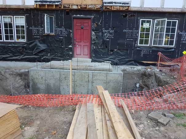 A red door is sitting in front of a building under construction.