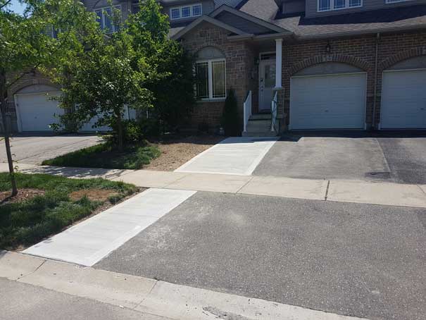 A brick house with a driveway and a sidewalk in front of it.