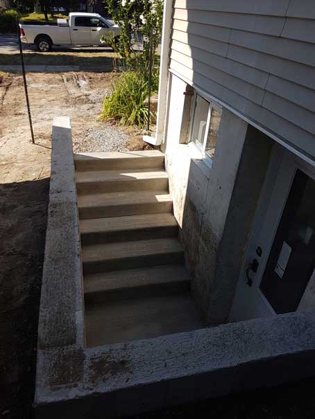 A white truck is parked in front of a house with stairs leading up to it.