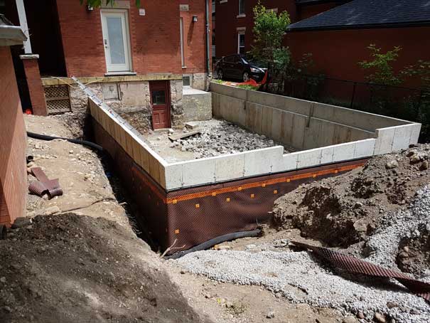 A concrete wall is being built in front of a brick house.