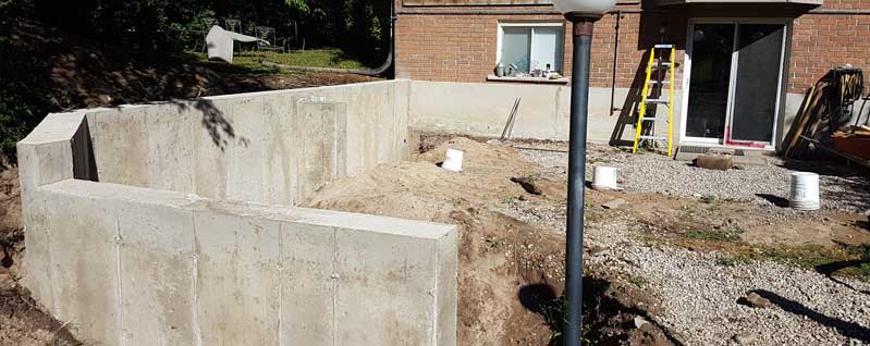 A concrete wall is being built in the backyard of a house.