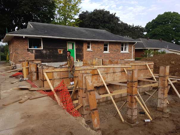 A man is standing in front of a house under construction