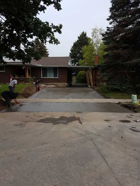 A man is pushing a wheelbarrow in front of a house