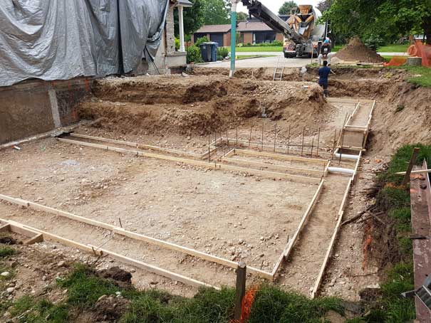 A construction site with a crane pouring concrete into the ground.