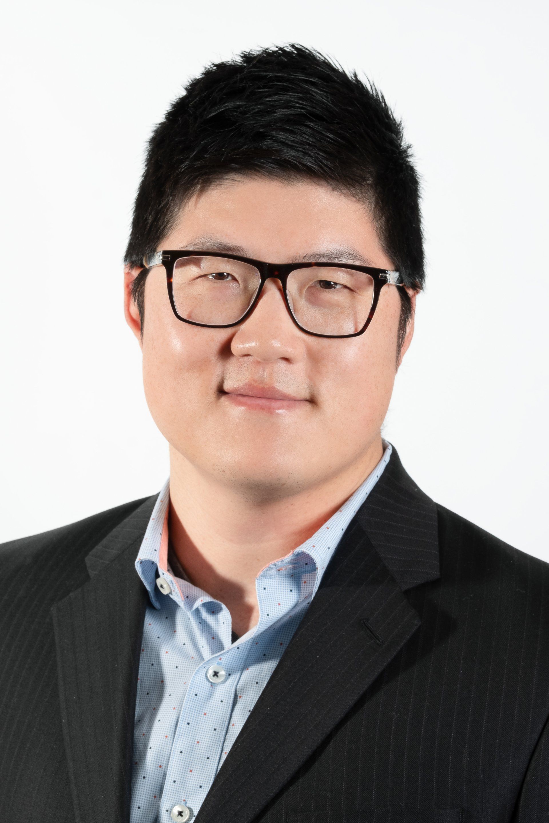 Asian man in suit and glasses posing for a Portrait Photography package with De Vera Imagery