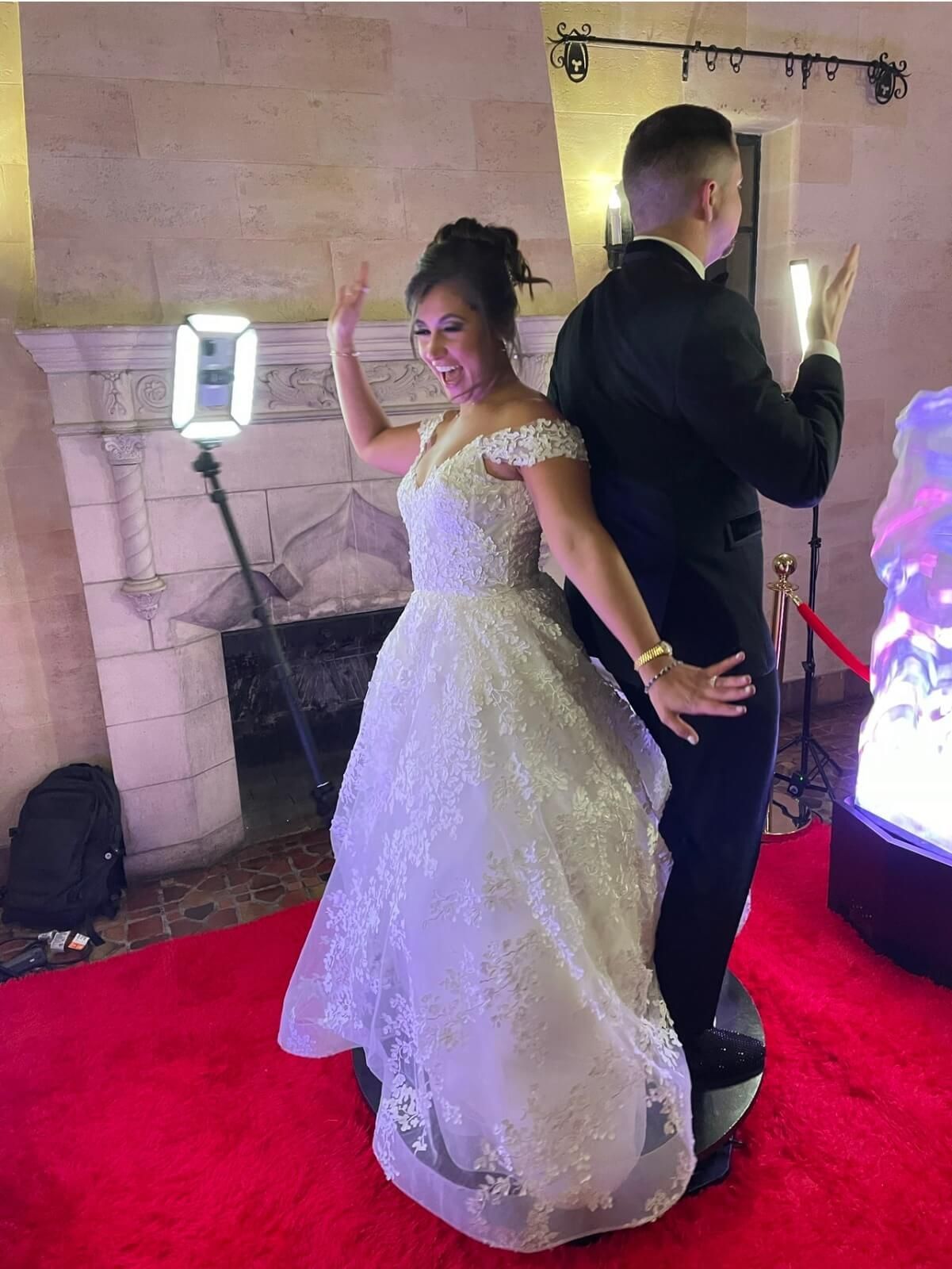 A bride and groom are posing for a picture on a red carpet.