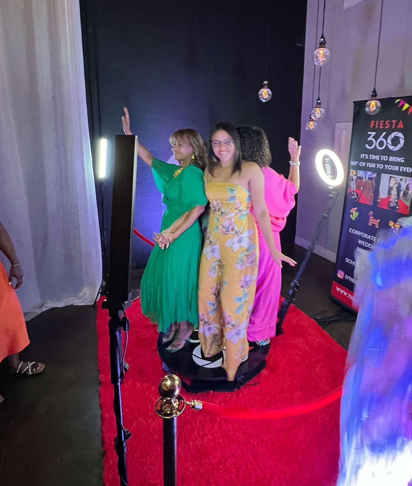 A woman is standing on a red carpet in front of a photo booth.