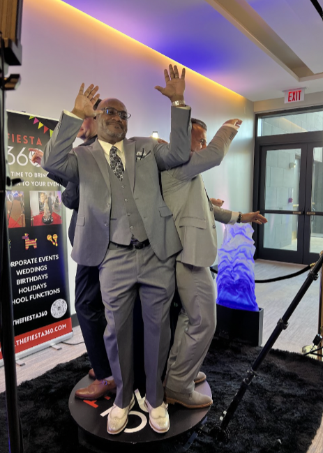 Two men in suits are posing for a photo on a 360 degree photo booth