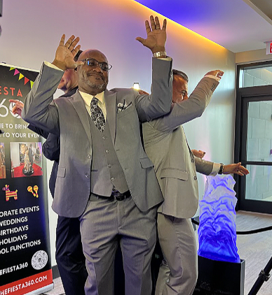 Two men in suits are posing for a photo on a 360 degree photo booth